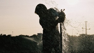 رجل يصلح رشاشة مياه في حقل في عيميك خيفر. (illustrative photo: Gili Yaari /Flash90)