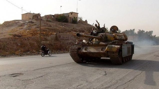 مقاتل موال للنظام يرفع إشارة النصر في 21 أغسطس، 2016، وهو يستقل دبابة في حي غويران في مدينة الحسكة شمال شرق سوريا، حيث كانت تتقدم القوات الكردية. (AFP/STR) مقاتل موال للنظام يرفع إشارة النصر في 21 أغسطس، 2016، وهو يستقل دبابة في حي غويران في مدينة الحسكة شمال شرق سوريا، حيث كانت تتقدم القوات الكردية. (AFP/STR)