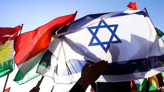 صورة تم التقاطها في 21 أكتوبر، 2017، تظهر رجلا يحمل العلم الإسرائيلي إلى جانب علام كردستان العراق خلال مظاهرة أمام مكتب الأمم المتحدة في إربيل، عاصمة الإقليم الذي يتمتع بالحكم الذاتي. (AFP Photo/Safin Hamed)