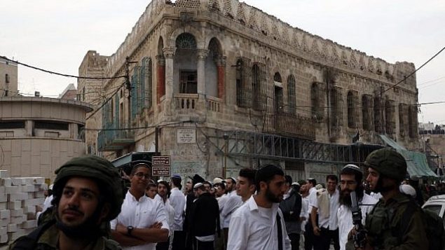 مستوطنون إسرائيليون ترافقهم قوات إسرائيلية خلال جولة في الجاب الفلسطيني من مدينة الخليل المقسمة، 18 نوفمبر، 2017. (AFP PHOTO / HAZEM BADER)