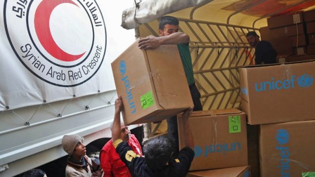 اطفال سوريون يراقبون توزيع رزم السماعدات من قبل اللجنة الدولية للصليب الاحمر في محافظة الغوطة في سوريا، 28 نوفمبر 2017 (AMER ALMOHIBANY / AFP)