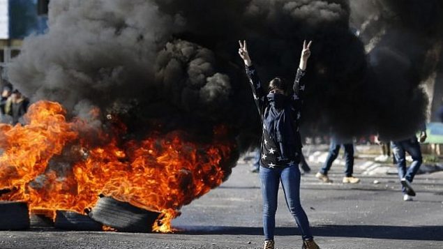 متظاهرة فلسطينية ملثمة خلال اشتباكات مع جنود اسرائيليين امام حاجز بالقرب من رام الله في الضفة الغربية، 8 ديسمبر 2017 (AFP PHOTO / ABBAS MOMANI)
