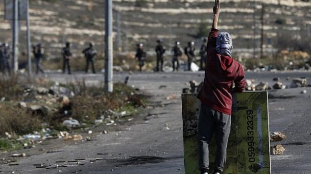 متظاهر فلسطيني ملثم خلال اشتباكات مع جنود اسرائيليين امام حاجز بالقرب من رام الله في الضفة الغربية، 8 ديسمبر 2017 (AFP PHOTO / ABBAS MOMANI)