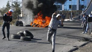 متظاهرون فلسطينيون يرشقون الحجارة باتجاه جنود اسرائيليين امام حاجز بالقرب من رام الله في الضفة الغربية، 8 ديسمبر 2017 (AFP PHOTO / ABBAS MOMANI)
