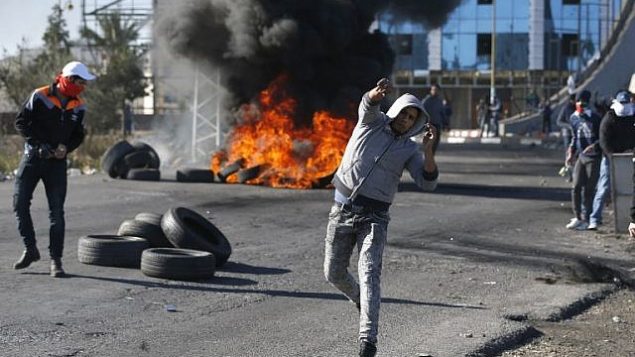 متظاهرون فلسطينيون يرشقون الحجارة باتجاه جنود اسرائيليين امام حاجز بالقرب من رام الله في الضفة الغربية، 8 ديسمبر 2017 (AFP PHOTO / ABBAS MOMANI)