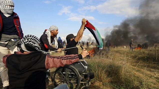 المتظاهر الفلسطيني المقعد ابراهيم ابو ثريا يلوح بالعلم الفلسطيني خلال مظاهرة امام السياج الحدودي مع اسرائيل، 15 ديسمبر 2017 (MOHAMMED ABED / AFP)