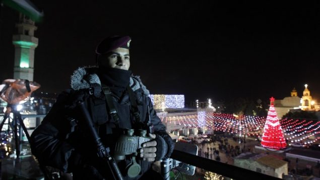 شرطي فلسطيني يقوم بحراسة ساحة المهد خارج كنيسة المهد مع احتشاد المحتفلين بليلة عيد الميلاد في مدينة بييت لحم في الضفة الغربية، 24 ديسمبر، 2017. (AFP PHOTO / Musa AL SHAER)