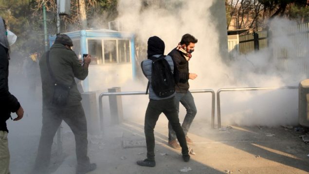 طلاب ايرانيون يفرون من الغاز المسيل للدموع في جامعة طهران خلال احتجاجات على الاوضاع الاقتصادية في البلاد، 30 ديسمبر 2017 (AFP PHOTO / STR)