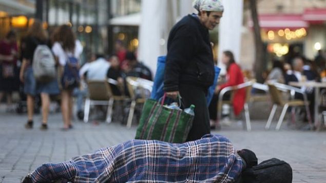 مارة يسيرون من أمام رجل مشرد ينام في الشارع، بالقرب من المقاهي في وسط مدينة القدس 10 نوفمبر، 2013. (Nati Shohat/FLASH90)