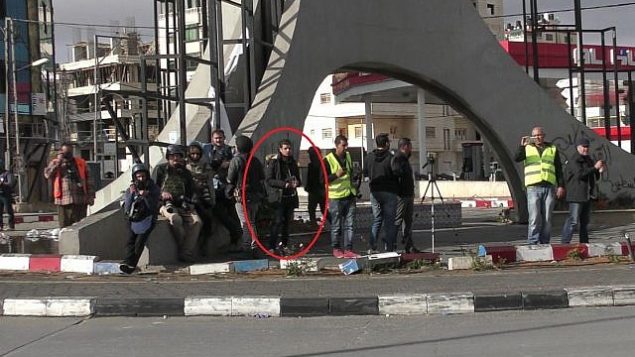 منفذ هجوم فلسطيني، يختبئ بين الصحافيين، قبل قيامه بطعن شرطي حرس حدود إسرائيلي في مدينة رام الله في الضفة الغربية، 15 ديسمبر، 2017. (الشرطة الإسرائيلية)