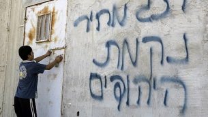 صورة توضيحية: صبي فلسطيني يفتح الباب بعد أن كتب على الجدران بالعبرية، ويزعم أن المستوطنون اليهود قاموا بذلك، في قرية عقربة في الضفة الغربية، بالقرب من مدينة نابلس، في 2 يوليو / تموز 2014. (AFP/JAAFAR ASHTIYEH)