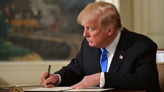 الرئيس الأمريكي دونالد ترامب يوقع مذكرة بعد أن أدلى ببيان عن القدس من غرفة الاستقبال الدبلوماسي في البيت الأبيض في واشنطن العاصمة يوم 6 ديسمبر 2017. (MANDEL NGAN/AFP)