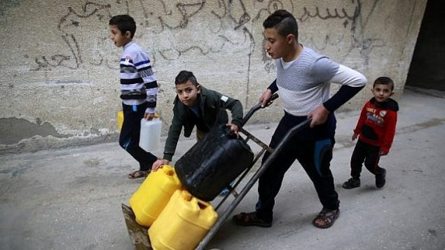 يحمل الأطفال الفلسطينيون المياه في مخيم الشاطئ للاجئين في مدينة غزة في 4 يناير / كانون الثاني 2018. (AFP PHOTO / MOHAMMED ABED)