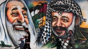 فلسطينيون يمرون بجدار يصور الرئيس الفلسطيني الراحل ياسر عرفات في مدينة غزة يوم الأربعاء 4 يوليو / تموز 2012. (Wissam Nassar/Flash90)
