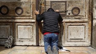أحد الحجاج يصلي من أمام الأبواب المغلقة لكنيسة القيامة في البلدة القديمة في مدينة القدس، 25 فبراير، 2018. (AFP PHOTO / GALI TIBBON)