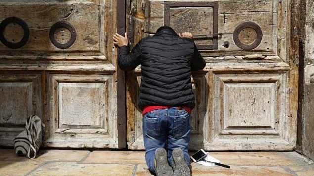 أحد الحجاج يصلي من أمام الأبواب المغلقة لكنيسة القيامة في البلدة القديمة في مدينة القدس، 25 فبراير، 2018. (AFP PHOTO / GALI TIBBON)