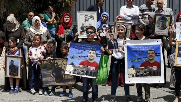 أسر أسرى فلسطينيين في السجون الإسرائيلية يتظاهرون أمام مكاتب الإتحاد الأوروبي في القدس الشرقية، 27 أبريل، 2017. (AFP/AHMAD GHARABLI)