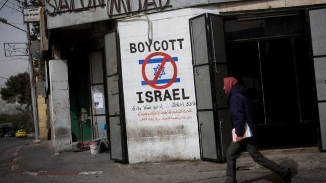 رجل فلسطيني يمر من أمام  رسم على جدار يدعو إلى مقاطعة إسرائيل في أحد شوارع مدينة بيت لحم في الضفة الغربية، 11 فبراير، 2015. (Miriam Alster/Flash 90)