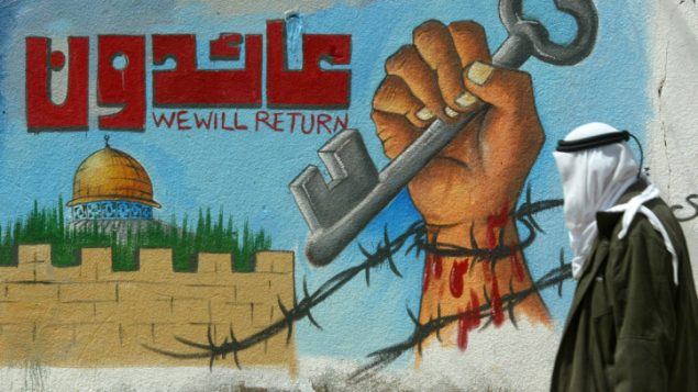 رجل فلسطيني يمر امام جدارية تنادي لعودة اللاجئين الفلسطينيين (Abed Rahim Khatib/Flash90)
