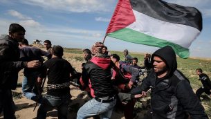 فلسطينيون يساعدون في إخلاء متظاهر مصاب خلال مواجهات مع القوات الإسرائيلية، بالقرب من خان يونس، عند السياج الحدودي بين إسرائيل وجنوب قطاع غزة، في 9 مارس، 2018. (AFP PHOTO / SAID KHATIB)