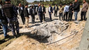 أفراد من قوات الأمن التابعة لحماس يتفقدون الفوهة التي تُركت في موقع الانفجار الذي استهدف موكب رئيس الوزراء الفلسطيني أثناء زيارته لقطاع غزة، بالقرب من معبر إيريز، في 13 مارس / آذار 2018. (AFP PHOTO / MAHMUD HAMS) )