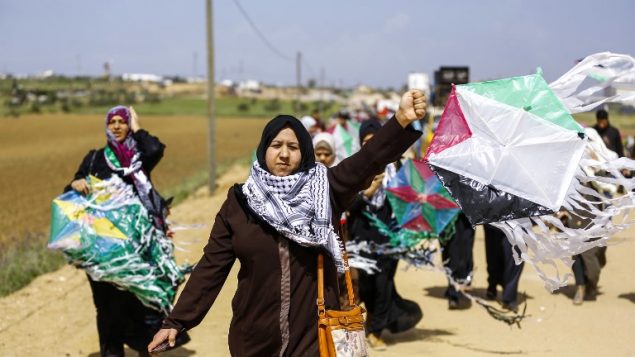 نساء فلسطينيات يطيرن طائرات ورق بألوان العلم الفلسطيني خلال مظاهرة قبل يوم الارض، في مدينة خيام واقعة بالقرب من الحدود بين اسرائيل وغزة، 29 مارس 2018 (AFP PHOTO / MOHAMMED ABED)