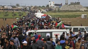 فلسطينيون يسيرون امام مدينة الخيام التي اقيمت امام الحدود مع اسرائيل شرقي مدينة غزة في يوم الارض، 30 مارس 2018 (AFP/ MAHMUD HAMS)