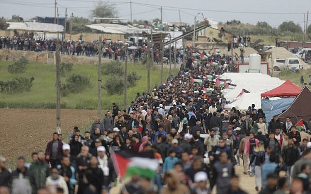 فلسطينيون يسيرون امام مدينة الخيام التي اقيمت امام الحدود مع اسرائيل شرقي مدينة غزة في يوم الارض، 30 مارس 2018 (AFP/ MAHMUD HAMS)