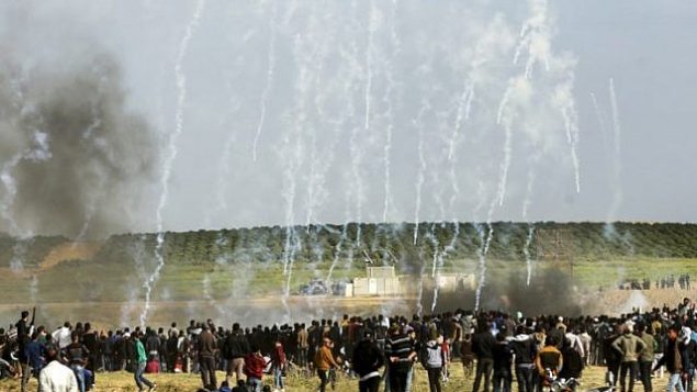 متظاهرون فلسطينيون يفرون بحثاً عن غطاء من الغاز المسيل للدموع الذي أطلقته القوات الإسرائيلية خلال اشتباكات في أعقاب مظاهرة تخلد ذكرى يوم الأرض، قرب الحدود مع إسرائيل، شرق مدينة غزة  في 30 مارس / آذار 2018. (AFP/Mahmud Hams)