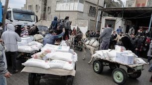 فلسطينيون يجمعون طرود مساعدات في مركز توزيع الغذاء التابع للأمم المتحدة في خان يونس الواقعة جنوب قطاع غزة، 28 يناير، 2018. (Said Khatib/AFP)