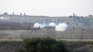 توضيحية: متظاهرون فلسطينيون بالقرب من السياج الحدود الإسراءئيلي مع قطاع غزة والجيش الإسرائيلي يطلق قنابل الغاز المسيل للدموع باتجاههم، 3 يناير، 2014. (David Buimovitch/Flash90)