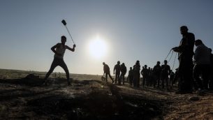 متظاهر فلسطيني يقذف الحجارة باتجاه الجنود الإسرائيليين خلال مظاهرة عند الحدود مع إسرائيل، شرقي مدينة غزة، 31 مارس، 2018.  (AFP PHOTO / MAHMUD HAMS)
