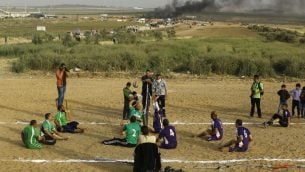 فلسطينيون ذوي اعاقات يلعبون الكرة الطائرة بالقرب من موقع الاشتباكات بين متظاهرين فلسطينيين وقوات الامن الإسرائيلية في اعقاب مظاهرات امام الحدود بين غزة واسرائيل، شرقي مدينة غزة، 5 ابريل 2018 (AFP/MOHAMMED ABED)