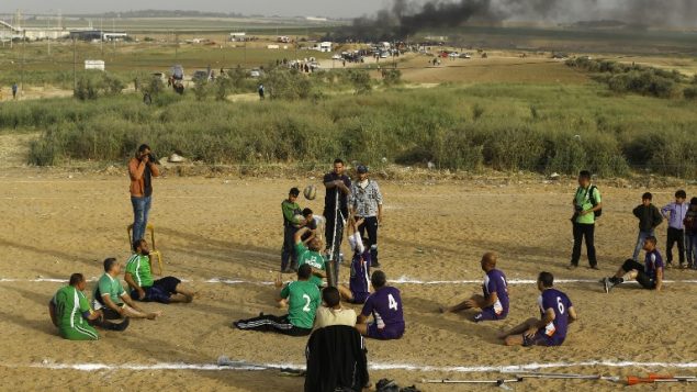 فلسطينيون ذوي اعاقات يلعبون الكرة الطائرة بالقرب من موقع الاشتباكات بين متظاهرين فلسطينيين وقوات الامن الإسرائيلية في اعقاب مظاهرات امام الحدود بين غزة واسرائيل، شرقي مدينة غزة، 5 ابريل 2018 (AFP/MOHAMMED ABED)
