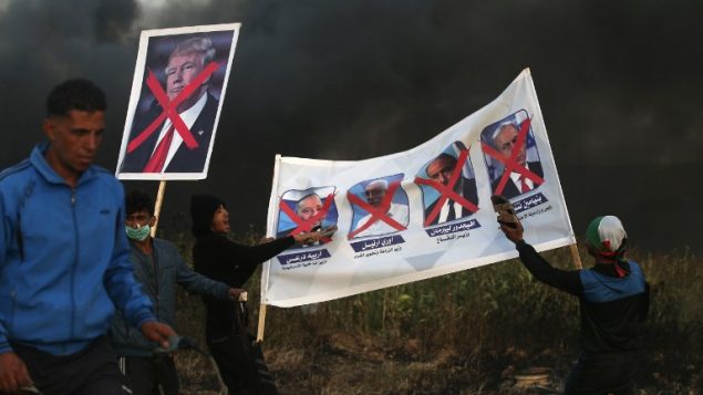 متظاهرون فلسطينيون يحملون لافتات عليها صور سياسيين اسرائيليين والرئيس الامريكي دونالد ترامب خلال اشتباكات مع قوات الامن الإسرائيلية في اعقاب مظاهرة امام الحدود مع اسرائيل، شرقي مدينة غزة، 5 ابريل 2018 (AFP PHOTO / MOHAMMED ABED)
