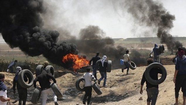 فلسطينيون يشعلون الاطارات للحماية من القناصين الإسرائيليين خلال اشتباكات عند الحدود بين غزة واسرائيل، 6 ابريل 2018 (MAHMUD HAMS / AFP)