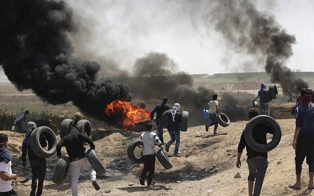 فلسطينيون يشعلون الاطارات للحماية من القناصين الإسرائيليين خلال اشتباكات عند الحدود بين غزة واسرائيل، 6 ابريل 2018 (MAHMUD HAMS / AFP)