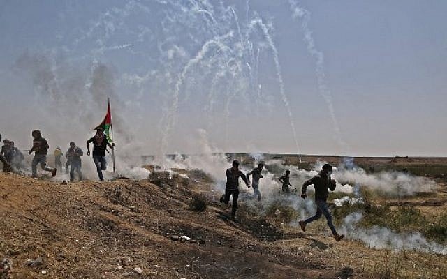 رجال فلسطينيون يهرعون للحماية من عبوات الغاز المسيل للدموع على الحدود بين إسرائيل وغزة خلال مظاهرة، شرق مدينة غزة في قطاع غزة، في 6 أبريل 2018. (AFP PHOTO / MAHMUD HAMS)