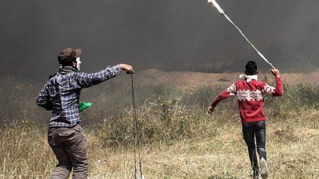 متظاهرون فلسطينيون يستخدمون المقاليع لرشق القوات الإسرائيلية بالحجارة خلال مواجهات عند حدود غزة مع إسرائيل في جنوب قطاع غزة، 6 أبريل، 2018. (AFP PHOTO / SAID KHATIB)