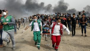 مسعفون فلسطينيون يخلون متظاهر مصاب خلال اشتباكات مع القوات الإسرائيلية في 20 أبريل 2018، شرق مدينة غزة، في جنوب قطاع غزة خلال احتجاجات جماهيرية على طول حدود الجيب الفلسطيني، أطلق عليها اسم "مسيرة العودة العظيمة" ، بدعم من الحكام الإسلاميين في غزة حماس. (MOHAMMED ABED / AFP)