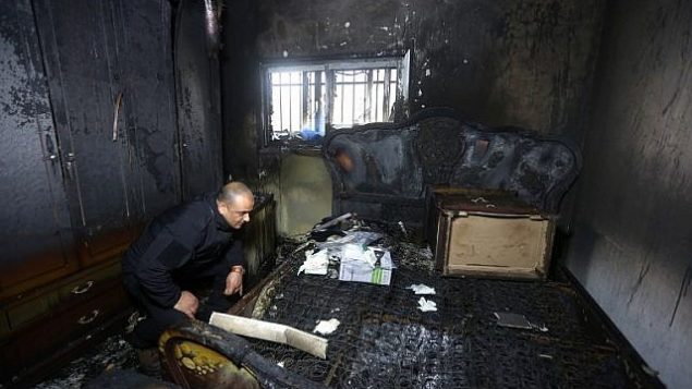 صورة توضيحية: شرطي فلسطيني يتفقد الأضرار داخل منزل محترق في حادثة اضرام نار في العام الماضي قام بها متطرفون يهود أسفرت عن مقتل عائلة فلسطينية، في قرية دوما بالضفة الغربية، في الساعات الأولى من يوم 20 مارس 2016. (AFP / Jaafar Ashtiyeh)