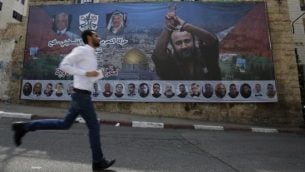 فلسطيني يمر من أمام ملصق يحمل صورة للقيادي والأسير الفلسطيني مروان البرغوثي في مدينة رام الله في الضفة الغربية، 3 مايو، 2017.  (AFP/ ABBAS MOMANI)