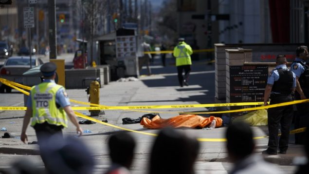 TORONTO, ON - APRIL 23: A tarp lays on top of a body on Yonge St. at Finch Ave. after a van plowed into pedestrians on April 23, 2018 in Toronto, Canada. A suspect is in custody after a white van collided with multiple pedestrians.   Cole Burston/Getty Images/AFP