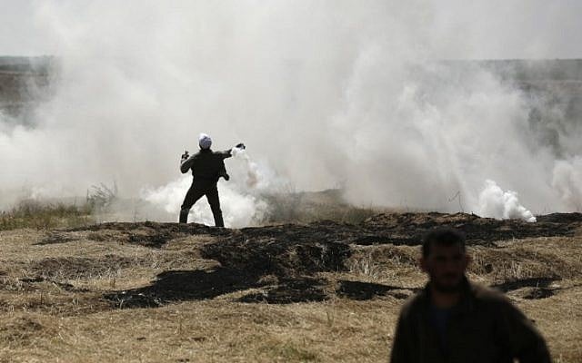 رجل فلسطيني يرمي عبوة غاز مسيل للدموع على الحدود بين إسرائيل وغزة خلال مظاهرة ، شرق مدينة غزة في قطاع غزة ، في 6 أبريل / نيسان 2018. (AFP PHOTO / MAHMUD HAMS)