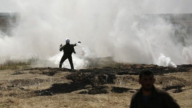 رجل فلسطيني يلقي قنبلة غاز مسيل للدموع بخلال اشتباكات عند الحدود بين غزة واسرائيل، 6 ابريل 2018 (MAHMUD HAMS / AFP)