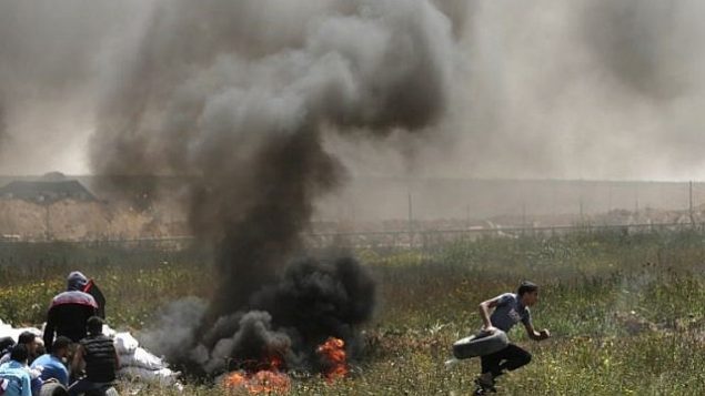 فلسطينيون يشعلون الاطارات للحماية من القناصين الإسرائيليين خلال اشتباكات عند الحدود بين غزة واسرائيل، 6 ابريل 2018 (MAHMUD HAMS / AFP)