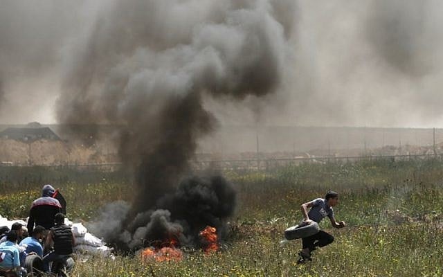 فلسطينيون يشعلون الاطارات للحماية من القناصين الإسرائيليين خلال اشتباكات عند الحدود بين غزة واسرائيل، 6 ابريل 2018 (MAHMUD HAMS / AFP)
