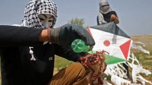 فلسطينيون عند الضواحي الشرقية لمدينة غزة يحضرون زجاجة حارقة لربطها بطائرة ورقية وتطييرها فوق السياج الحدودي مع إسرائيل، 20 أبريل، 2018.  (AFP Photo/Mohammed Abed)