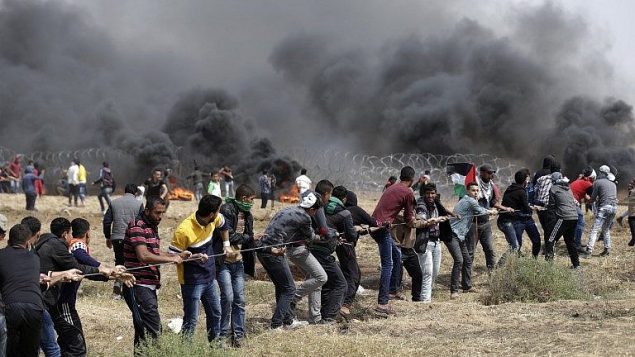 فلسطينيون يحاولون إسقاط جزء من السياج الحدودي بين إسرائيل وغزة شرق جباليا في شمال قطاع غزة، خلال خامس يوم على التوالي من التظاهرات على طول الحدود بين غزة وإسرائيل، في 27 أبريل، 2018. (AFP Photo/Mahmud Hams)
