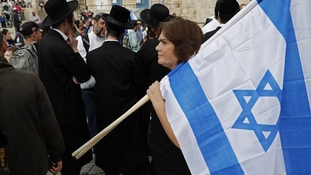 امرأة تحمل العلم الإسرائيلي خلال مسيرة للاحتفال ب’يوم القدس’ في ذكرى توحيد المدينة خلال حرب 1967، 13 مايو 2018 (Thomas COEX/AFP)